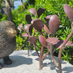 一株株銅葉舒展枝姿，在陽光下閃耀生命的光澤，鳥兒靜靜守望，為街道增添自然的詩意。