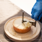 半硬質(zhì)家族的修道士(TETE DE MOINE)，呈小型鼓狀，外殼有點油膩、呈褐色，乳酪團結(jié)實且濃郁，隨著熟成顏色會加深，以轉(zhuǎn)臺式乳酪削切器，削成花摺邊小花苞。