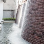 與接待大廳相對，僅隔一道玻璃落地窗即為「戶外水瀑牆」。流水潺潺與磚石沖刷出平整的紋路，水光相映下霧氣生騰，彷若仙境。－【新業(yè)觀峰】。
