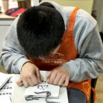 小羊苗朋友將臉湊近提袋上，仔細(xì)將貼紙慢慢地貼上，盡可能確保貼紙有貼正不歪斜。從肢體動作，可以曉得小羊們做每件事比別人費(fèi)力，但不減心意。