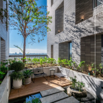 四季合院，每三層設(shè)計(jì)一處公共大露臺(tái)，從梯廳走入彷彿大家庭的合院(埕)，提供住戶們休憩及交誼空間，搭配四季主題的呼應(yīng)，此為七樓的夏季-種植小花紫薇與厚葉石斑木。