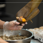 將粽葉三分之一處折起，交叉形成漏斗狀，轉(zhuǎn)著處末端折一個(gè)折角，再將內(nèi)餡包入。