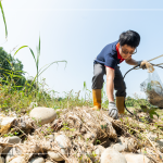 從石縫中抽出韌性的橡膠圈，岸邊的垃圾也不可輕忽，可能會(huì)因?yàn)闈q潮後的潮水而沖刷到溪裡。