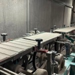 乾燥處理過的磁磚，整齊地陳列在輸送臺上，準備進入下一道逐層施釉的工序。