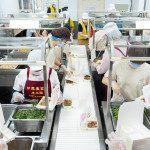 新業(yè)同仁與甘霖志工們分工合作，以生產(chǎn)線的方式有序地進行，將熱騰騰的餐食迅速裝盒，確保長輩能準時享用午餐。